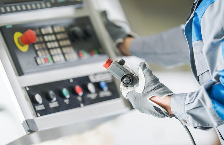 A technician operates a control panel with a handheld device in a medical setting.